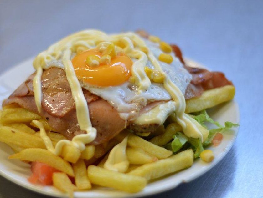 Chivito al plato con jamón, huevo frito, choclo y mayonesa sobre papas fritas