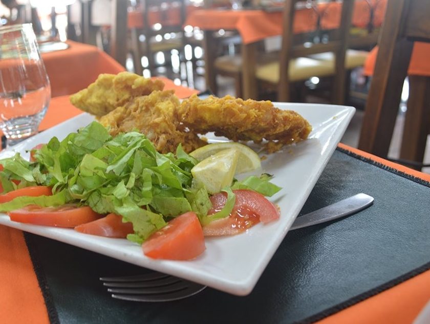 Filetes rebozados con una rodaja de limón y ensalada de lechuga y tomate, servidos en una mesa del salón